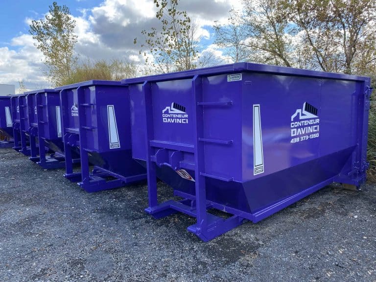 Row of purple industrial waste containers with Conteneur Davinci branding lined up outdoors on gravel ground under a partly cloudy sky