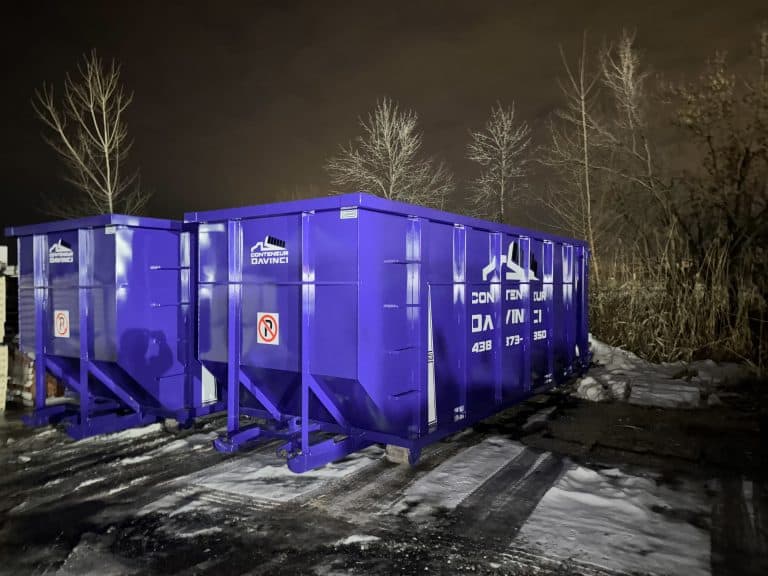Large blue Conteneur Davinci dumpsters placed outdoors at night with bare trees and snow ground